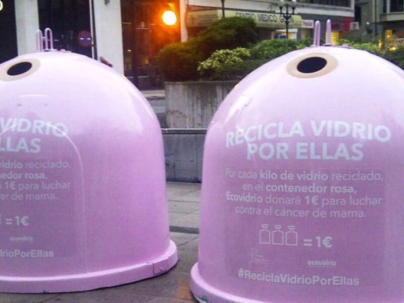Dos contenedores de vidrio rosa con información sobre reciclaje y donaciones para la lucha contra el cáncer de mama.