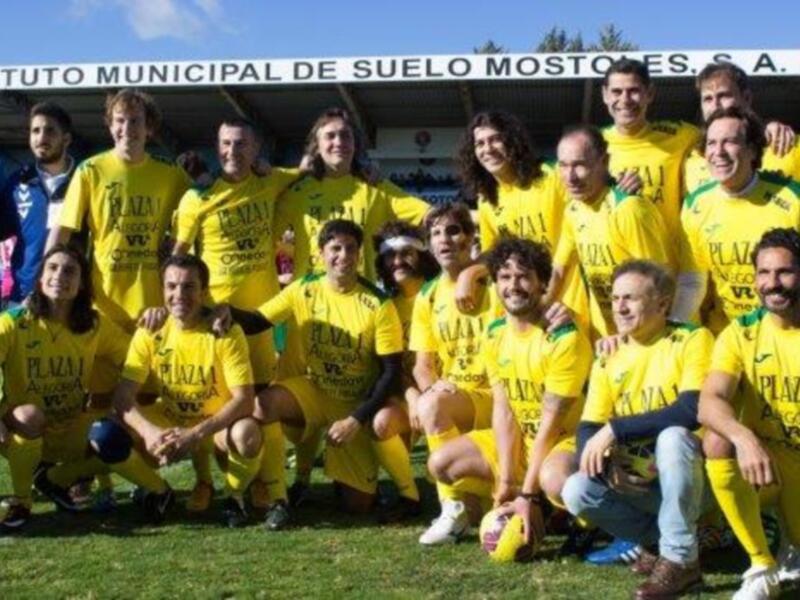 Equipo de fútbol en uniforme amarillo posando para una foto de equipo en un campo de fútbol.