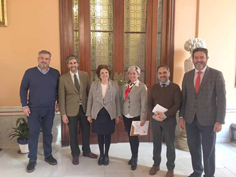 Grupo de profesionales posando en un salón con vitrales, vestidos de manera formal.