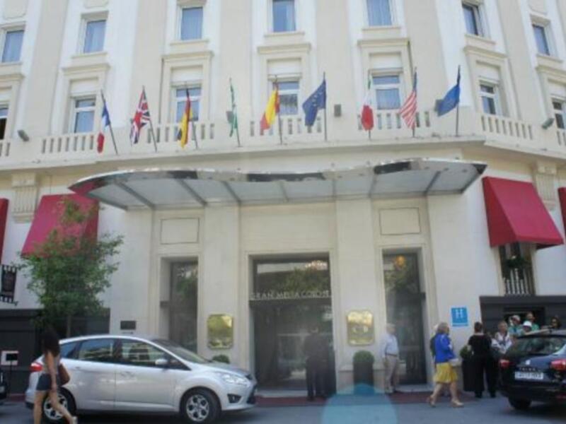 Entrada del Gran Hotel Metropol, con banderas internacionales y sombreadores rojos.