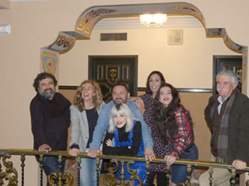 Grupo de personas sonrientes posando juntos en un balcón con detalles ornamentales.