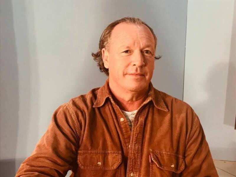 Retrato de hombre con camisa marrón, fondo neutro