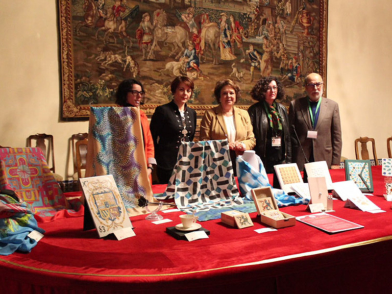 Exposición de textiles y artesanía en un ambiente histórico con personas participantes.