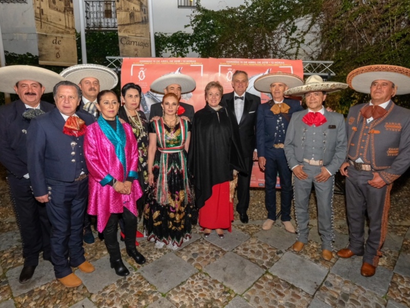 Grupo de personas en trajes típicos mexicanos posando juntos en un evento al aire libre.