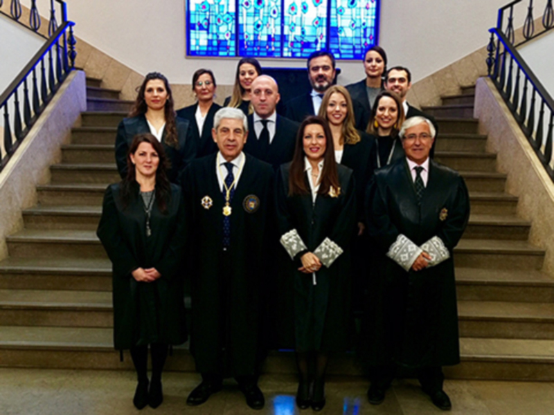 Gruppo di professionisti in abiti ufficiali posano per un ritratto di gruppo in un'ambiente formale.