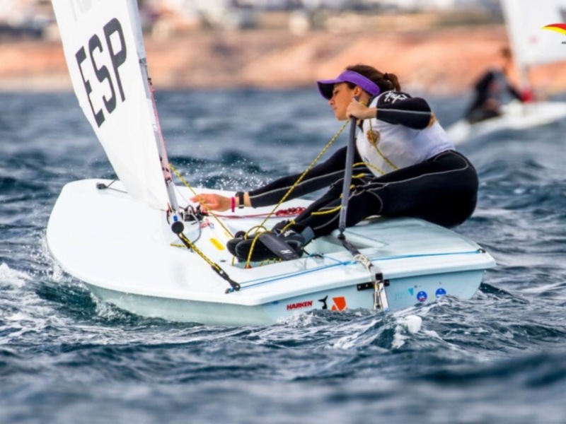 Competitiva en acción: una regatista española navega con destreza en su barco de vela en el mar abierto.