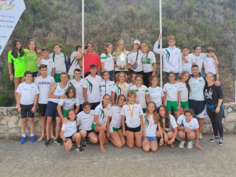 Equipo deportivo celebrando con trofeo y medallas en un entorno montañoso.