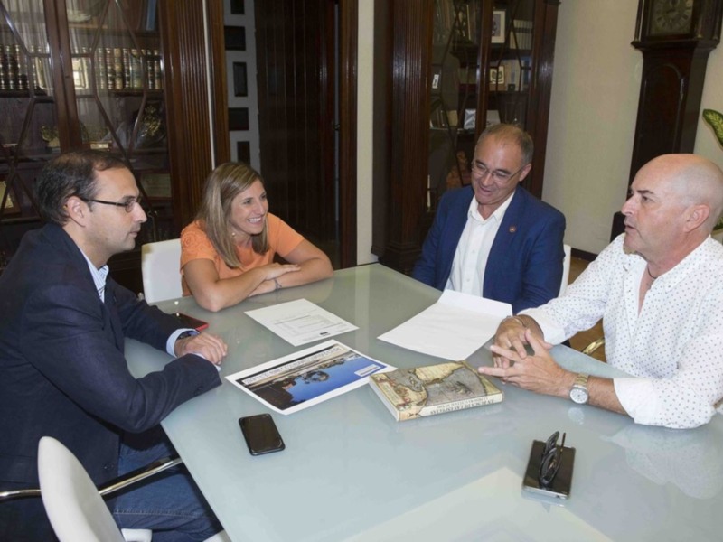 Reunión de trabajo en una sala formal con documentos y un libro en la mesa.