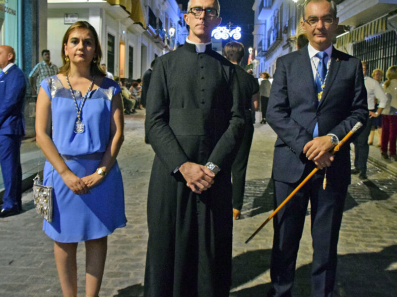 Personajes en trajes formales en una calle nocturna iluminada.