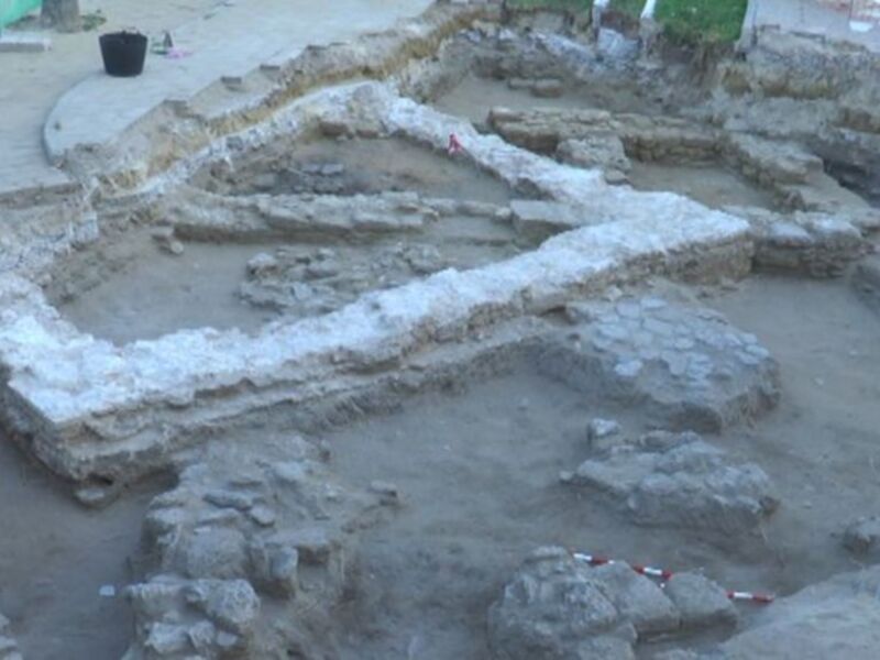 Ruinas arqueológicas de una estructura antigua en proceso de excavación, con evidencias de edificios y muros en el terreno.