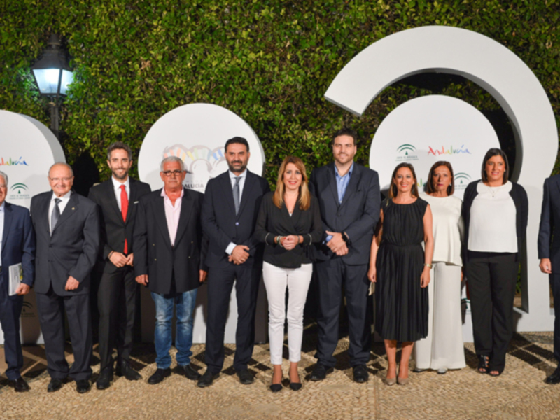 Grupo de personas en un evento de Andalucía, posando frente a un fondo verde y logotipos