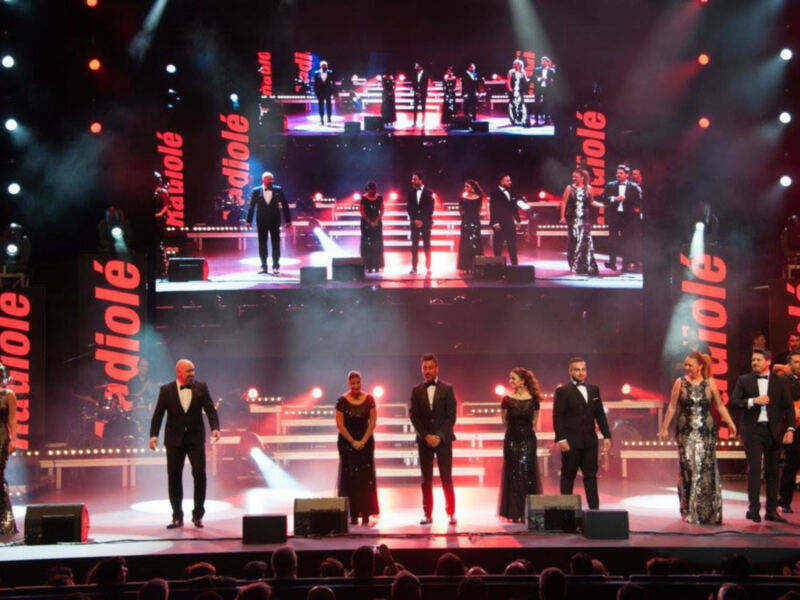 Grupo musical en escenario con luces y efectos de neblina, presentando un espectáculo en vivo.