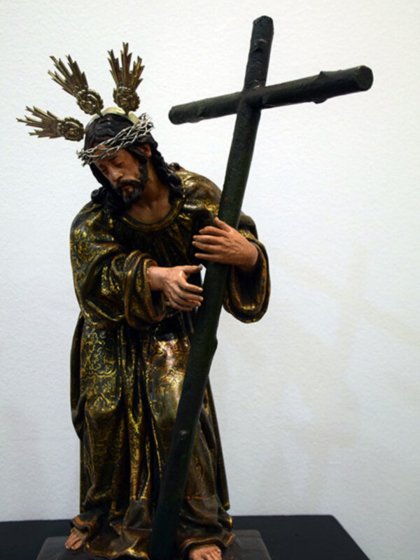Representación escultórica de Jesús cargando la cruz, vestido con túnicas doradas y corona de espinas.