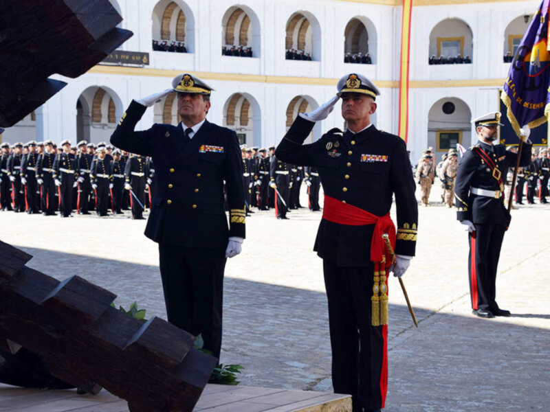 Oficiales militares saludando durante una ceremonia en un patio de armas.