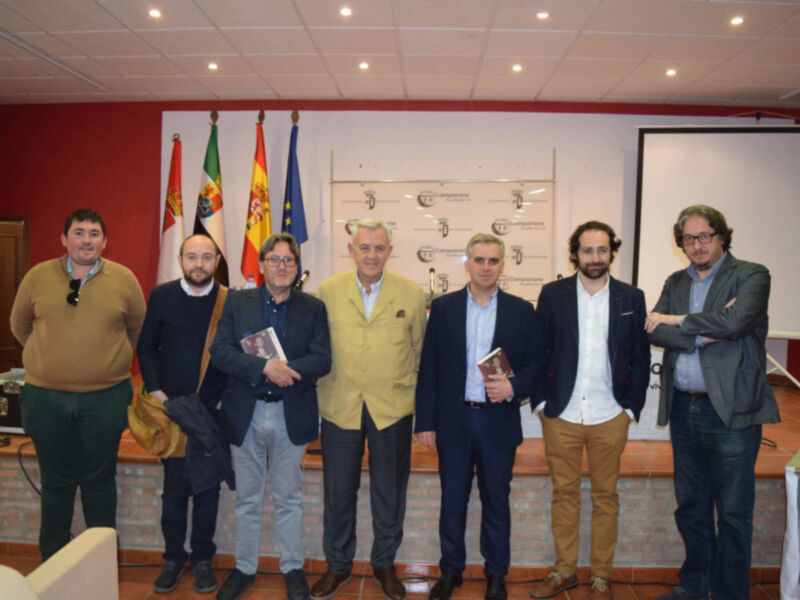 Grupo de personas posando en una reunión formal, con banderas y un cartel en el fondo.