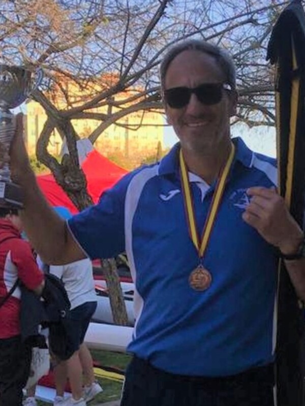 Hombre celebrando con trofeo y medalla, posando con orgullo en un evento deportivo.