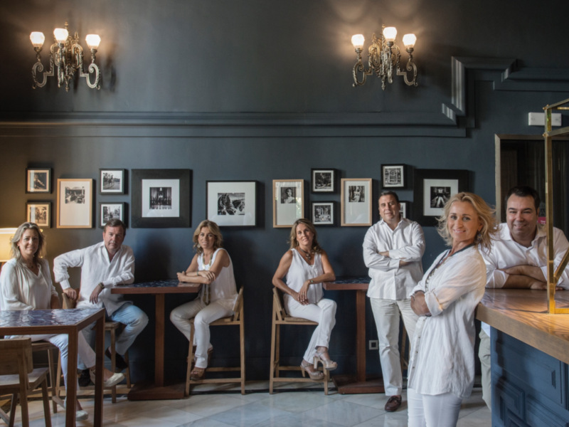 Equipo de profesionales en un ambiente elegante con decoración clásica y arte enmarcado en la pared.