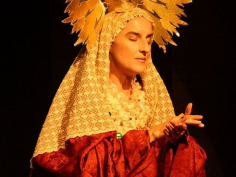 Actriz en traje de época, con capa dorada y roja, representando un personaje histórico o mitológico.