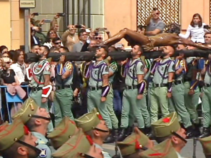 Desfile militar con soldados en uniforme y público observando.