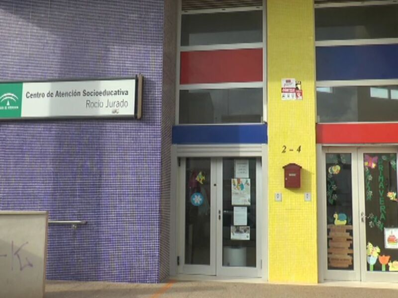 Centro de Atención Socioeducativa Rocio Jurado, con una fachada azul, amarilla y roja, y un cartel en la puerta indicando su nombre.