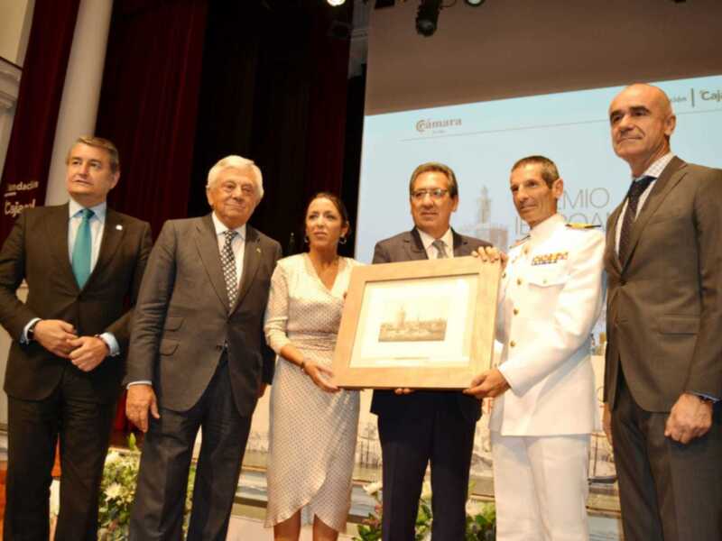Entrega de un premio en un evento formal en una sala de conferencias.