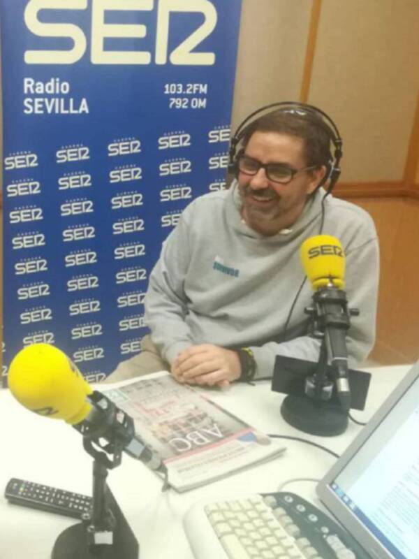 Presentador en estudio de Radio SER Sevilla, con micrófono y material de trabajo.