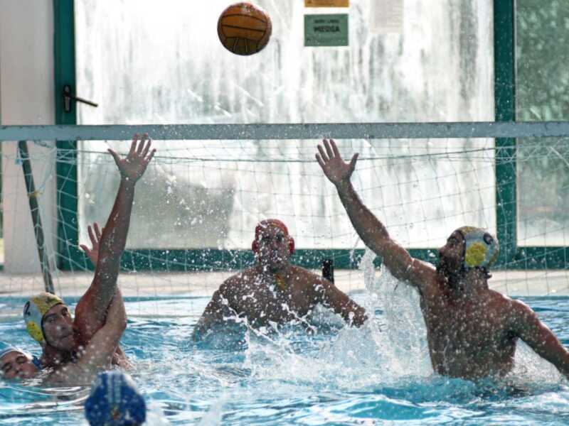 Jugadores de waterpolo en acción durante un partido, luchando por el balón en la piscina.