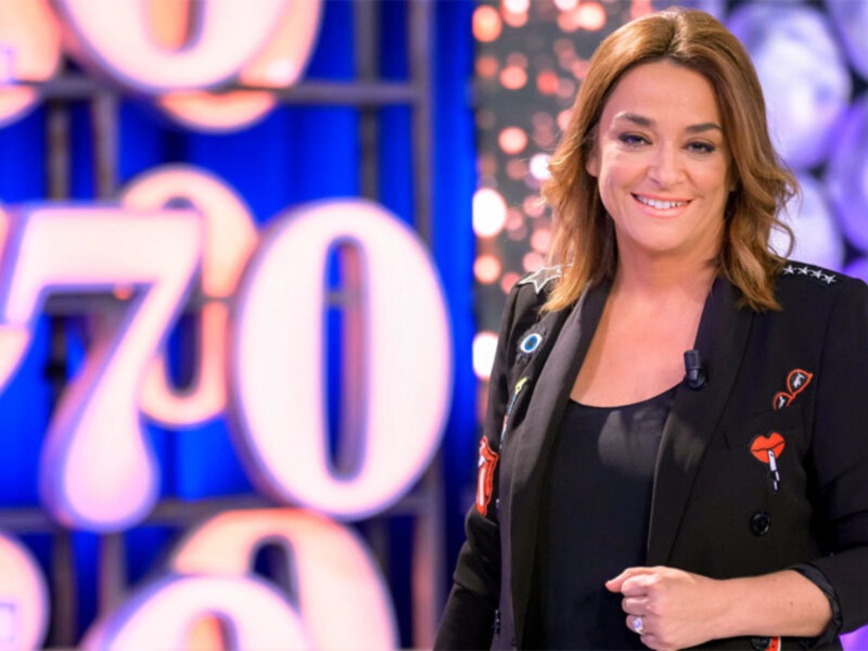 Presentadora en un estudio de televisión con fondo numérico y decoración brillante.