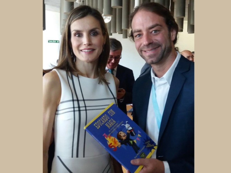 Una pareja sonríe en un evento, la mujer sostiene un libro titulado 'Edulcorando con Magia'.