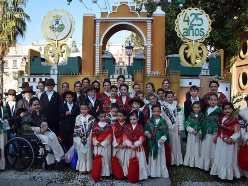 Un grupo de niños vestidos con trajes tradicionales posa frente a una estructura histórica con un letrero que dice '425 años'.