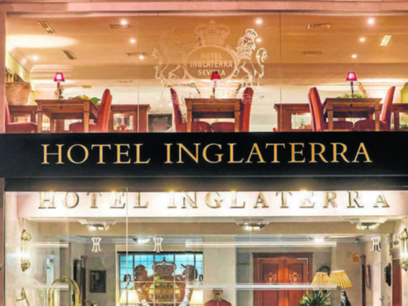 Hotel Inglaterra: Elegante fachada con entrada iluminada y detalles clásicos.