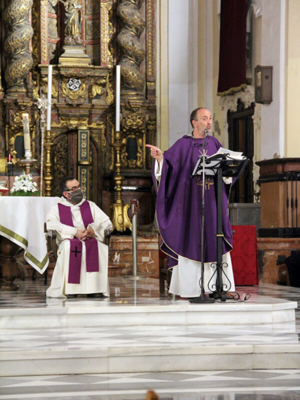 Celebración religiosa en una iglesia con un sacerdote en el altar y otro en el fondo, ambos vestidos con túnicas litúrgicas.
