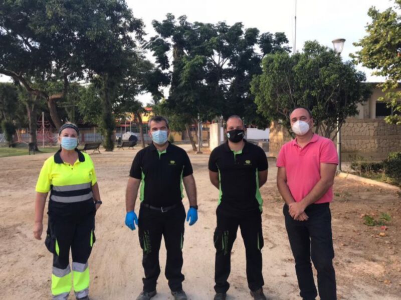 Equipo de limpieza con mascarillas y guantes en un parque.