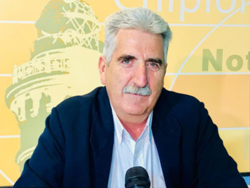 El hombre está en una conferencia de prensa, con un fondo amarillo que muestra la cúpula del Capitolio. Se puede ver una microondas en su frente y un fondo amarillo que muestra la cúpula del Capitolio.