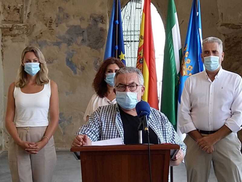 Persona hablando en un podium con máscaras y banderas en el fondo.