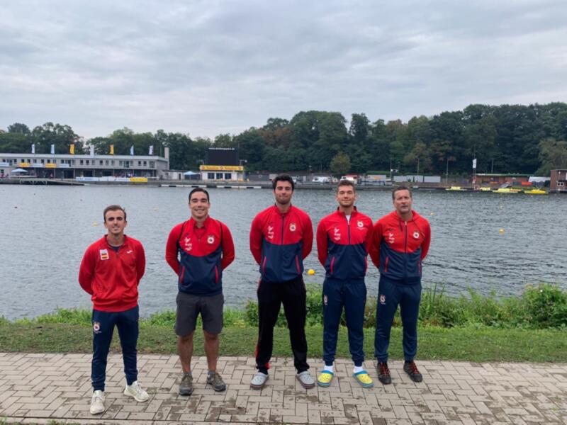 Equipo de remo posando junto al lago en un día nublado.