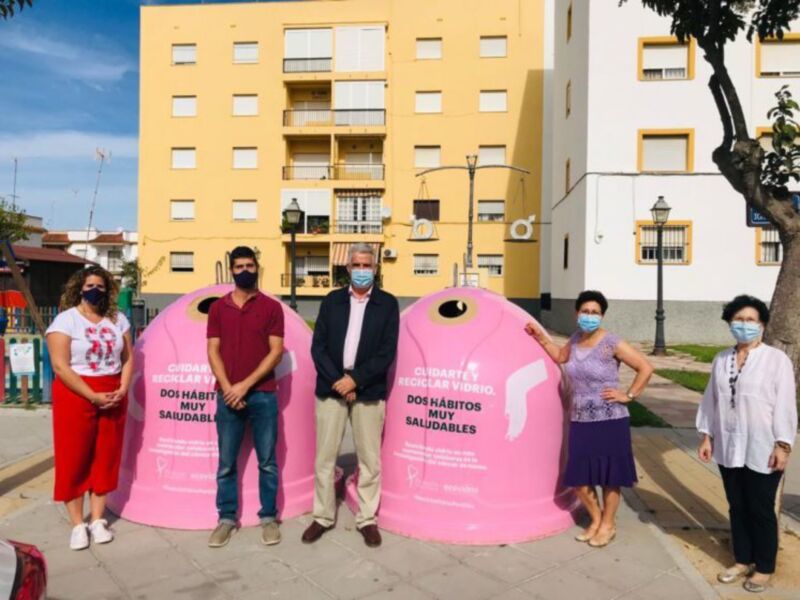 Personalidades locales posan junto a contenedores de reciclaje de vidrio en un barrio, destacando la importancia de la separación de residuos para una gestión más eficiente y ecológica.