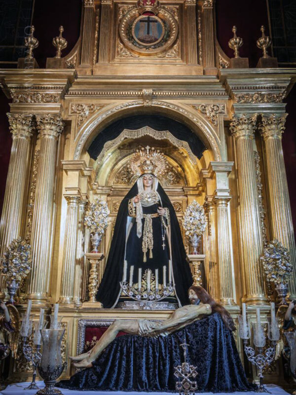 Imponente imagen de la Virgen de la Soledad en un altar ornado con dorado y decoraciones religiosas.