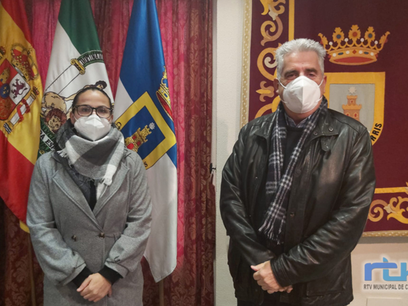 Dos personas posan frente a banderas y un escudo de Chipiona, con el logo de RTV Municipal de Chipiona en la esquina inferior derecha.