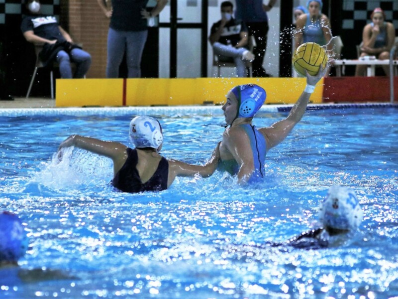 Jugadoras de waterpolo en acción durante un partido en piscina.