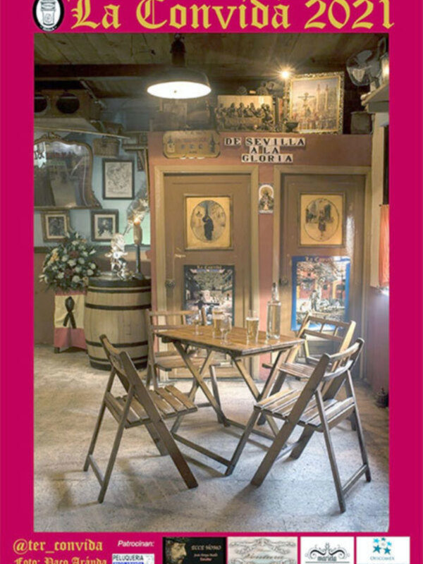Interior de un restaurante con mesa y sillas, decoración tradicional y cartel 'La Convidá 2021' en la parte superior.