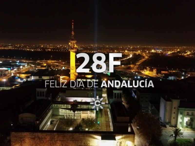 Vista nocturna de la ciudad de Sevilla, España, con el texto 'Feliz Día de Andalucía' superpuesto.