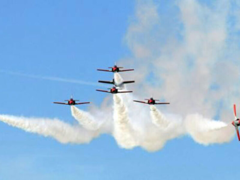 Aviones acrobáticos en vuelo con colinas en el fondo.