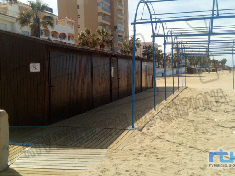 Playa de Chipiona con estructuras para el acceso a la playa y edificios en el fondo.