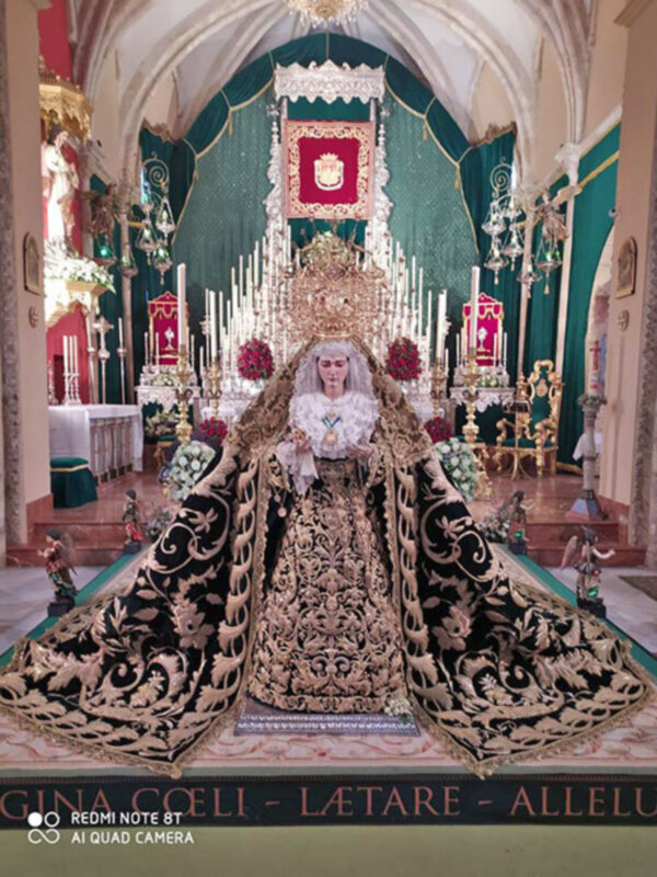 Procesión de la Virgen de la Candelaria en una iglesia ornada con candelabros y altares decorados.