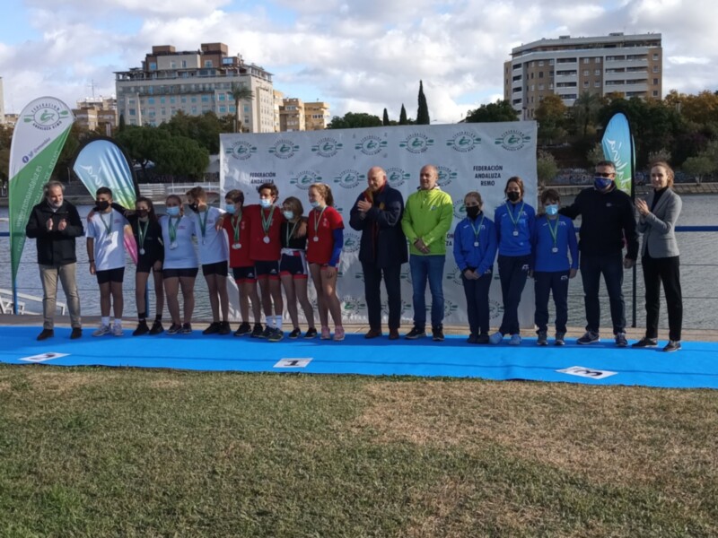 Equipo de remo celebrando una victoria en un evento deportivo, con medallas y sonrisas en el podio.