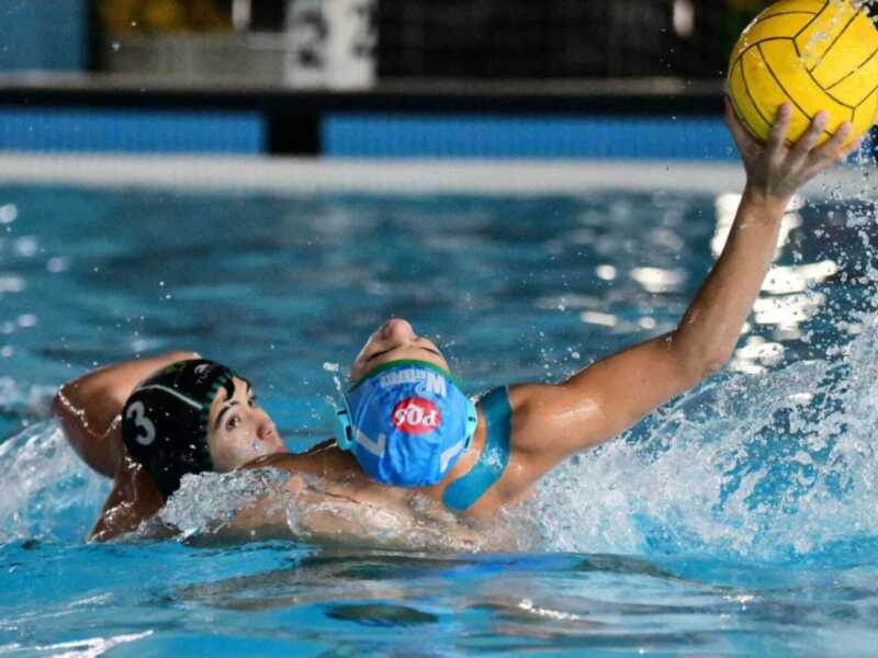 Jugador de waterpolo en acción, atrapando el balón en el agua durante un partido.