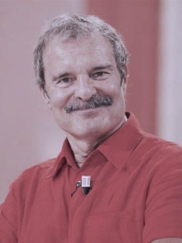 Retrato de hombre sonriente con camisa roja, fondo suave y neutro.
