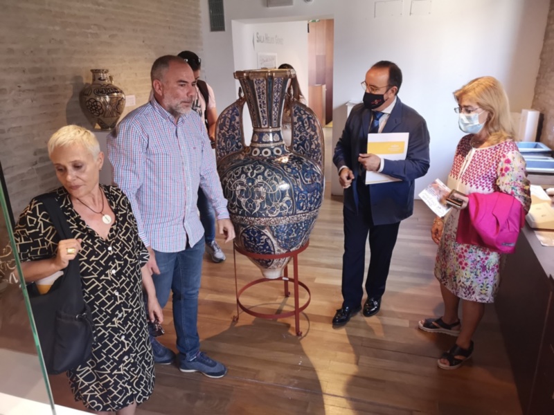 Visita guiada en un museo con un gran jarrón ornamental en el centro.