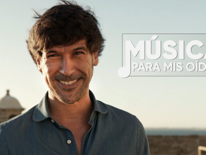 Un hombre sonriendo con un fondo de cielo claro y una torre en el horizonte, con el texto 'MÚSICA PARA MIS OÍDOS' en la parte superior derecha.
